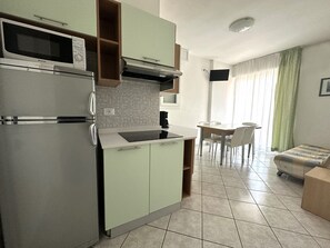 Una cucina compatta con forno a microonde, fornello e lavello. C'è un'area pranzo con tavolo e sedie.