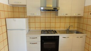 A compact kitchen with a refrigerator, stove, oven, and sink.