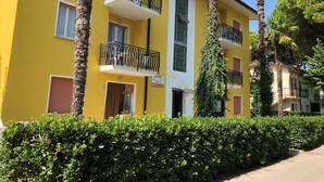 A yellow building with balconies, a sign reading "Villa Palma," and surrounding greenery.