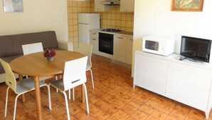 A compact kitchen with a dining area, a sofa, and a painting on the wall. - Peaceful Stay in Bibione Just 300mt From the sea (San Michele al Tagliamento)