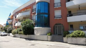 A multi-story hotel with balconies, a central tower, and a parking area. - Modern Apartment With Terrace (San Michele al Tagliamento)