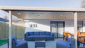 An outdoor patio with a covered seating area, including a sofa and two chairs, and a table with chairs. - VillaVerde 4BRs/Pool/Sleeps16/Gym/Gameroom/HTX/NRG (Houston)