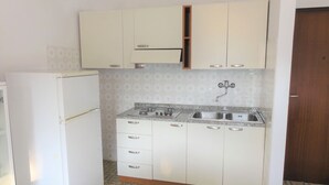 A compact kitchen with white cabinets, a built-in stove, and a sink. - Comfort and Calm in Bibione Near the sea (San Michele al Tagliamento)