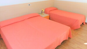 A room with two single beds, each covered with a pink bedspread, a small bedside table with a lamp, and a plain wall with a light switch. - Comfort and Calm in Bibione Near the sea (San Michele al Tagliamento)