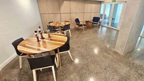 A modern conference room with round tables and black chairs, a polished concrete floor, and a wooden wall panel. - Stunning Beachfront 1BR Suite with Ocean View (Jacó)