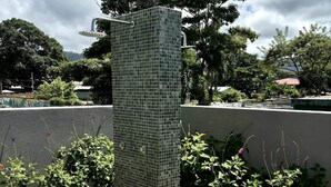 A tall, rectangular, tiled structure with a metal frame, surrounded by greenery and a wooden deck. - Stunning Beachfront 1BR Suite with Ocean View (Jacó)