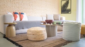 Ein Wohnzimmer mit Sofa, Hocker, Couchtisch und Wanddekoration.