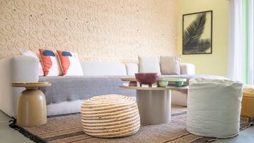 Un salon comprenant un canapé, un pouf, une table basse et des éléments de décoration murale.