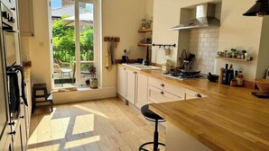 Uma cozinha com bancada de madeira, fogão e janela com vista para um jardim.