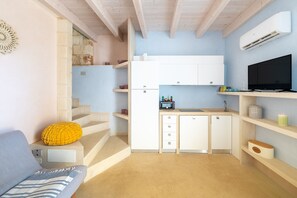 A compact kitchen with white cabinets, a built-in oven, a microwave, and a sink.
