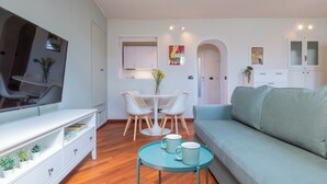 A modern living room with a sofa, a TV, a dining table with chairs, and a small coffee table with mugs. - Da Laura e Guido by Wonderful Italy (Turin)