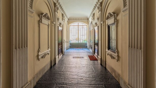 A grand hallway with ornate columns and a large arched window at the end. - Da Laura e Guido by Wonderful Italy (Turin)