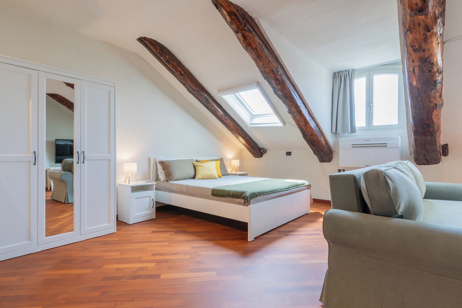 A bedroom with a sloped ceiling, a bed, a nightstand, a chair, and a wardrobe.