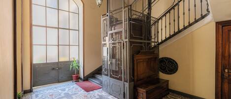 A staircase with a metal railing, a wooden bench, and a patterned floor.
