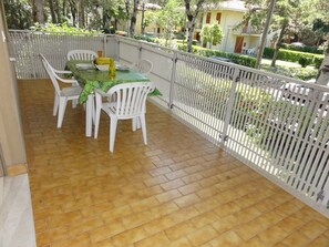 Ein Balkon mit Tisch und Stühlen, gefliestem Boden und einer weißen Brüstung.