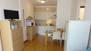 A compact kitchen with a dining area, a television, and a refrigerator.