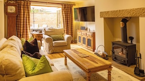 A cozy living room with a sofa, armchair, wooden coffee table, and a fireplace. - Welcome to The Coach House, a stunning converted coach house and stables in the peaceful village of Staxton, just a short drive from Scarborough and the beautiful Yorkshire Coast. Blending countryside character with contemporary luxury. (Scarborough)