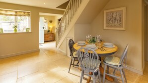 A dining area with a wooden table set for four, two chairs, and a staircase in the background. - Welcome to The Coach House, a stunning converted coach house and stables in the peaceful village of Staxton, just a short drive from Scarborough and the beautiful Yorkshire Coast. Blending countryside character with contemporary luxury. (Scarborough)