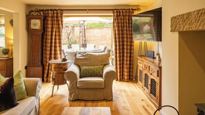 A cozy living room with a sofa, armchair, and a wooden cabinet. - Welcome to The Coach House, a stunning converted coach house and stables in the peaceful village of Staxton, just a short drive from Scarborough and the beautiful Yorkshire Coast. Blending countryside character with contemporary luxury. (Scarborough)