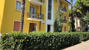 Keltainen rakennus, jossa on parvekkeita, ja sen yläpuolella oleva kyltti, jossa lukee ”Villa Palma”, sekä ympäröivä vehreä kasvillisuus.