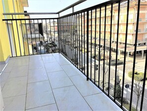 Un balcon doté d’un sol carrelé et d’une rambarde en métal.