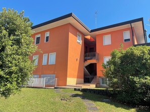 A multi-story building with a flat roof, a central staircase, and a balcony. - Quiet Apartment With Terrace (San Michele al Tagliamento)