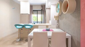 A modern dining area with a white table, two blue bar stools, and a pink placemat. - Apartment 'Biancomare Otranto - Apt 2' with Balcony, Wi-Fi and Air Conditioning (otranto)
