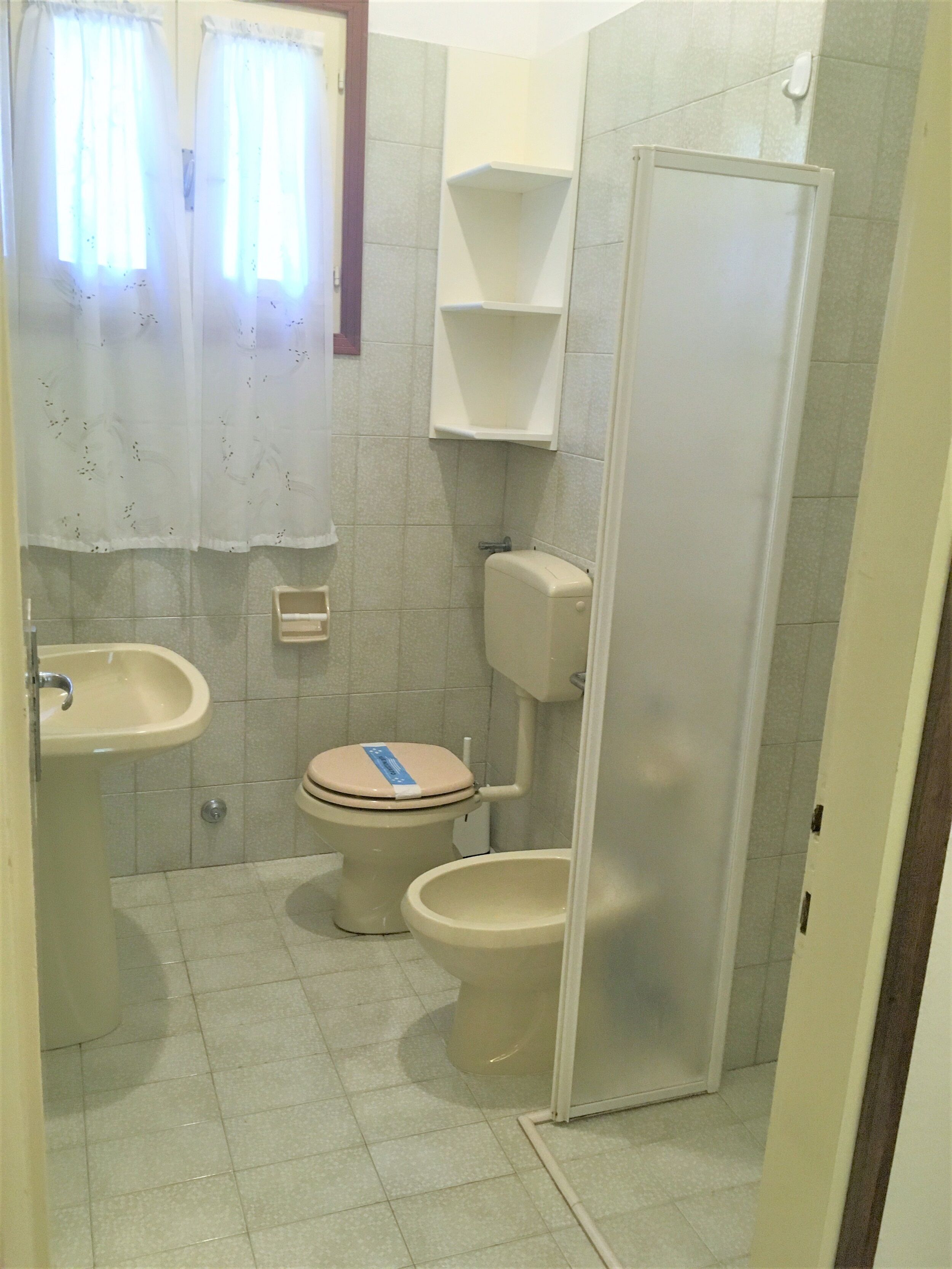 A small bathroom with a toilet, sink, and a shower stall.