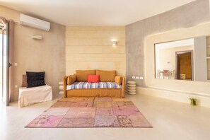 A modern living room with a sofa, a patterned rug, a small table, and a large mirror.