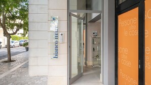 Entrada de un edificio con un cartel que dice 'bianco mare' y una puerta de vidrio adyacente.