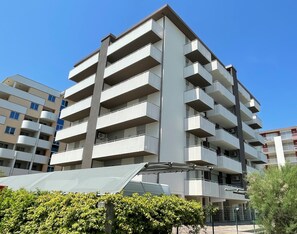 Un edificio residencial de varios pisos con balcones, techo plano y cielo despejado.