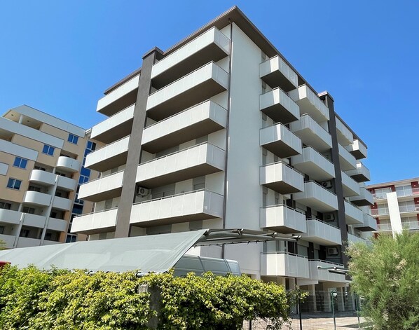 A multi-story residential building with balconies, a flat roof, and a clear sky.