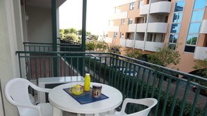 A balcony with a round table and two white chairs, a yellow bottle, and a small container. - Flat in a Modern Coastal Building (San Michele al Tagliamento)