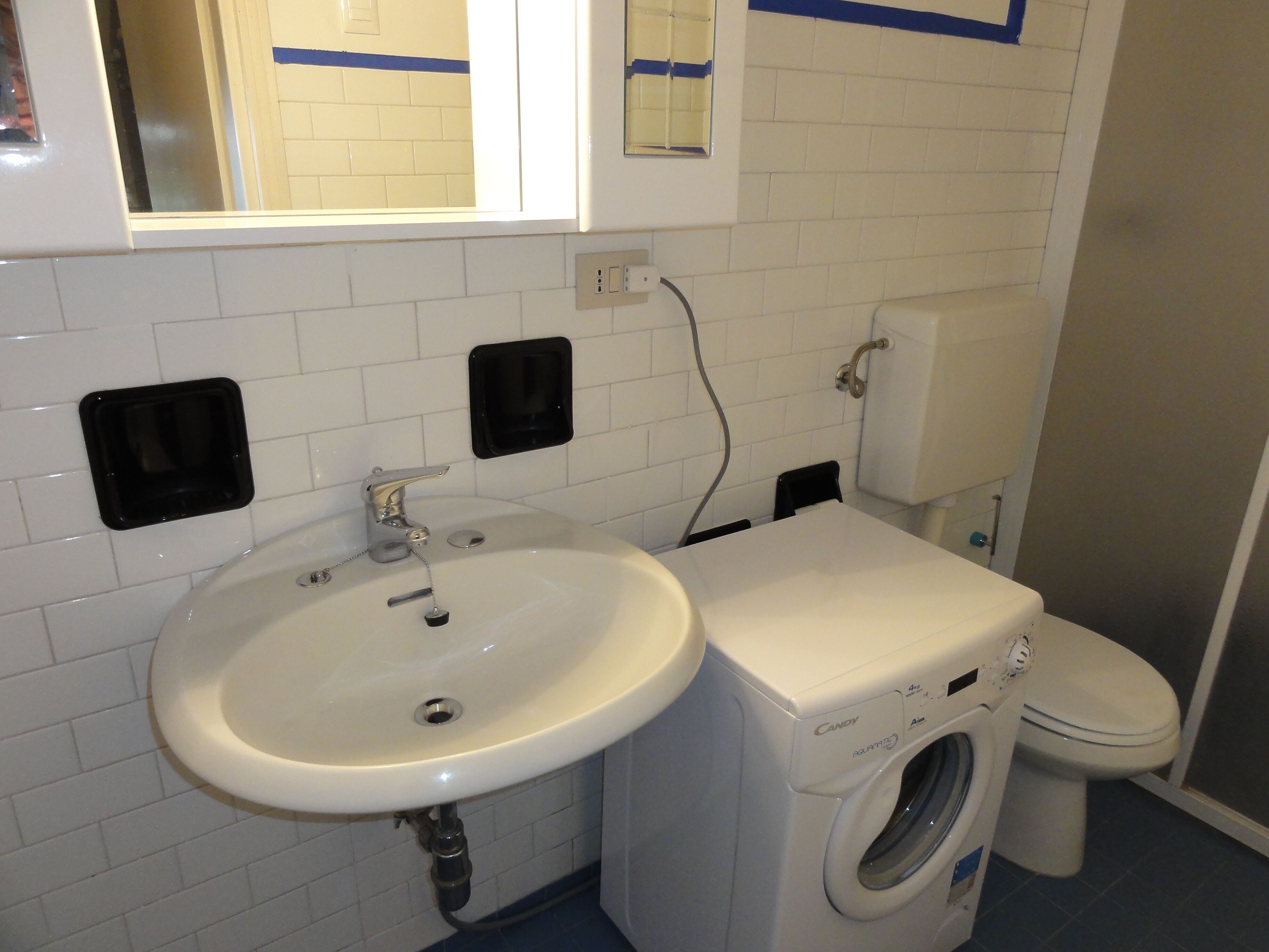Un baño con lavamanos, lavadora e inodoro.