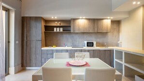 Una cocina moderna con una mesa de comedor de vidrio, sillas blancas y armarios empotrados.