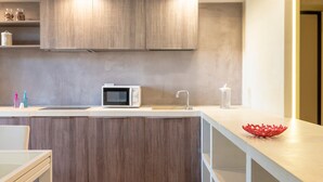 Una cocina moderna con armarios de madera, un microondas, un fregadero y un cuenco decorativo rojo sobre la encimera.