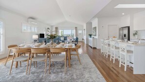 A spacious kitchen with a long island, white cabinetry, and a view to the outside.