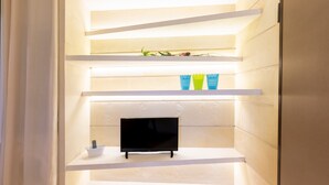 A modern interior with a flat-screen TV on a shelf, white walls, and a door. - Apartment 'Biancomare Otranto - 5' with Sea View, Wi-Fi and Air Conditioning (otranto)