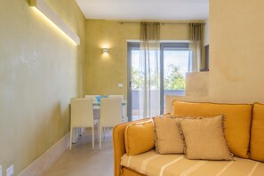 Une pièce comprenant un canapé, une table à manger, des chaises et une porte-fenêtre coulissante donnant sur un espace extérieur.