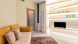 A modern living room with a sofa, a television, and a patterned rug. - Apartment 'Biancomare Otranto - 5' with Sea View, Wi-Fi and Air Conditioning (otranto)