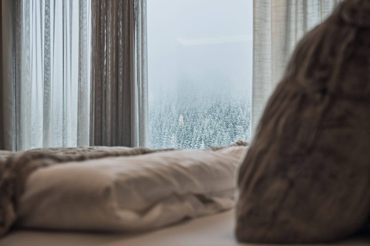 Ein Schlafzimmer mit Fensterblick auf eine verschneite Landschaft.