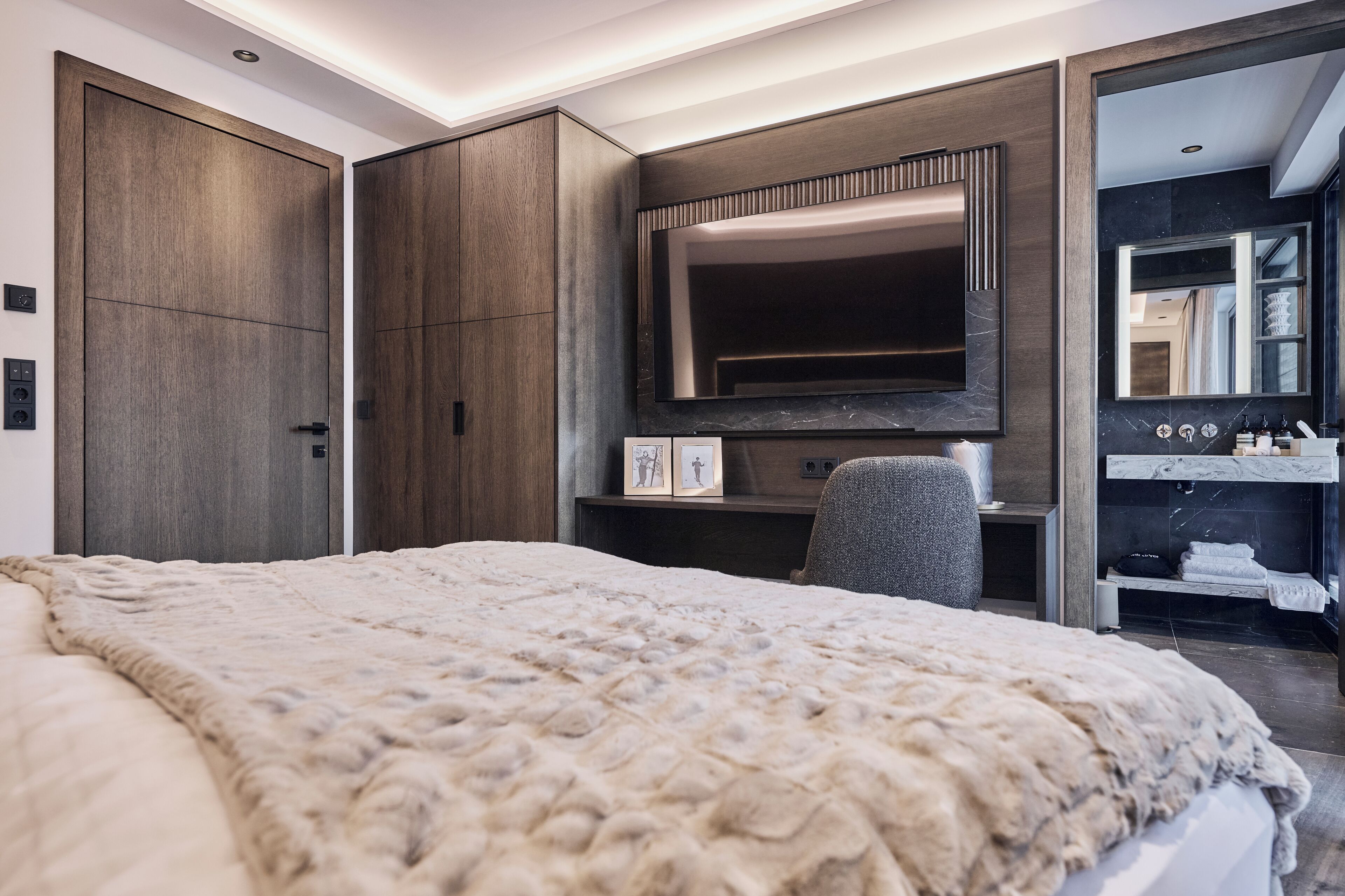 A modern bedroom with a large bed, a TV, and a built-in wardrobe.