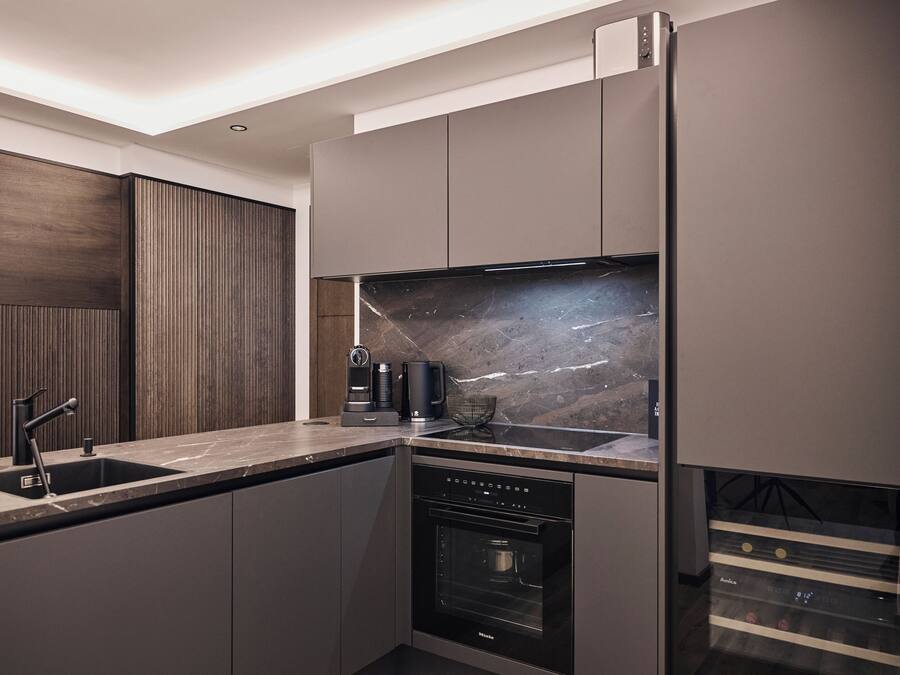 A modern kitchen with a built-in oven, a coffee maker, and a sink.