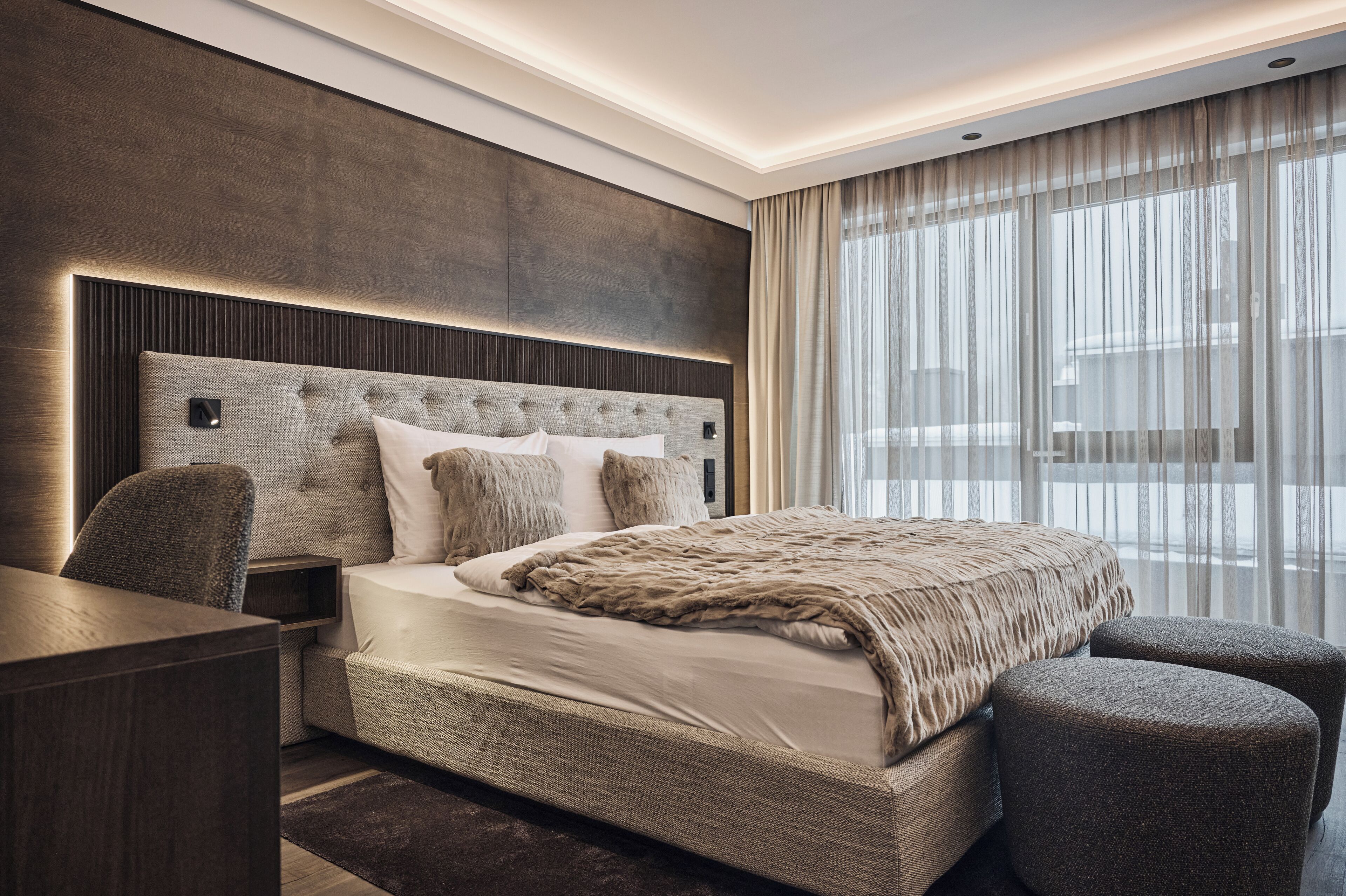 A modern hotel room with a large bed, a desk, and a chair.