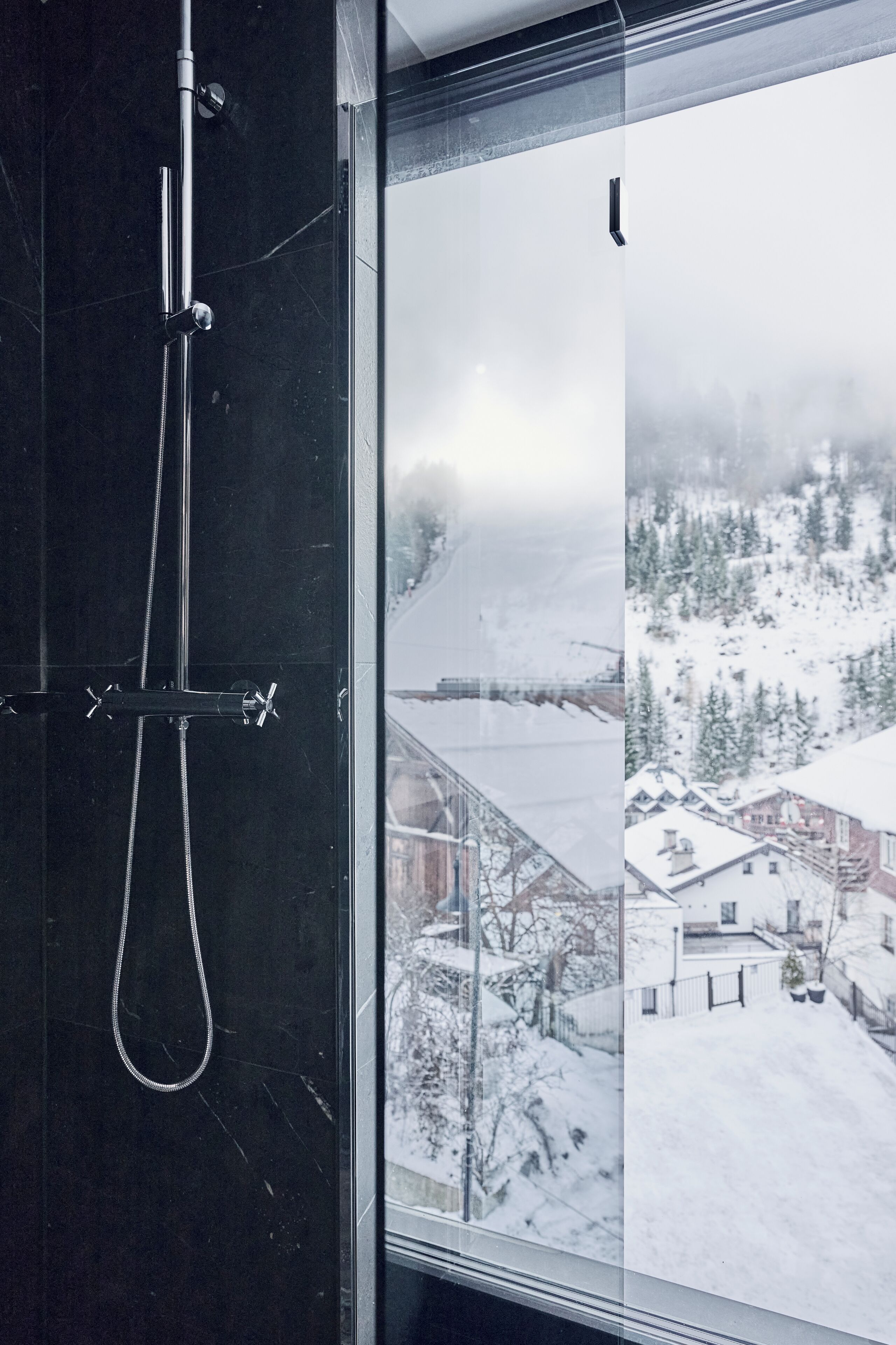 Baño con cabina de ducha de vidrio y vistas a un paisaje nevado de montaña.
