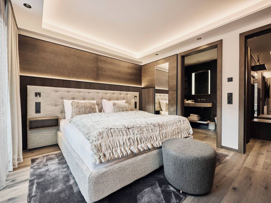 Un dormitorio moderno con una cama grande, una mesita de noche, un espejo y un armario.