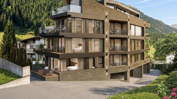 A modern multi-story hotel with a balcony, large windows, and a mountainous backdrop. - Chalet Ischgl - Modern Luxury Residences (Ischgl)