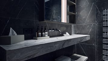 A modern bathroom with a marble countertop, a large mirror, and a towel rack.