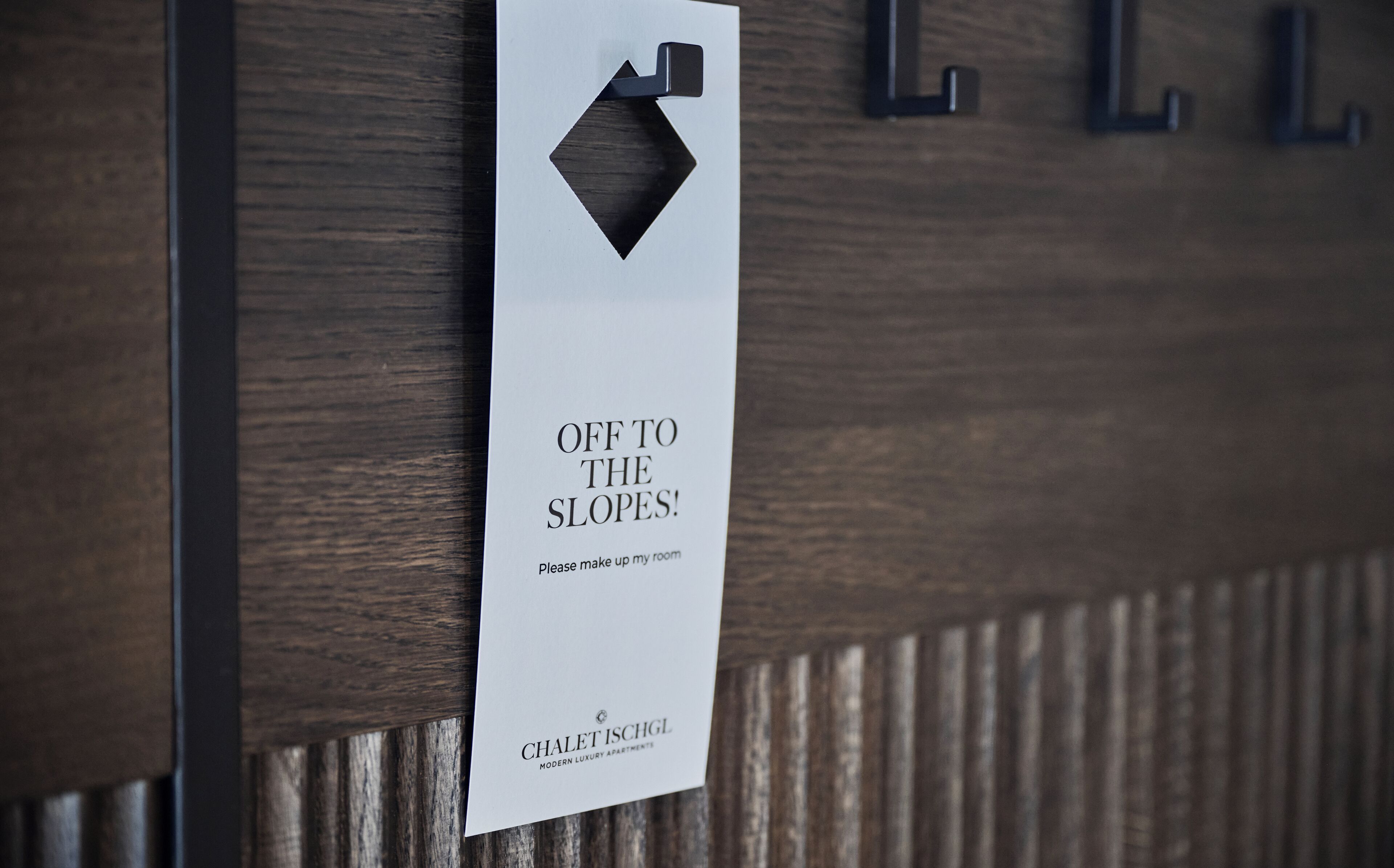 Une pancarte indiquant « EN ROUTE VERS LES PISTES ! » et « Merci de faire le ménage dans ma chambre », signalant la disponibilité du service d’étage.