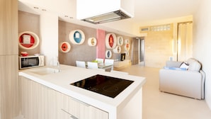 Een moderne keuken met een centraal eiland, ingebouwde apparatuur en een eethoek met een witte tafel en stoelen.